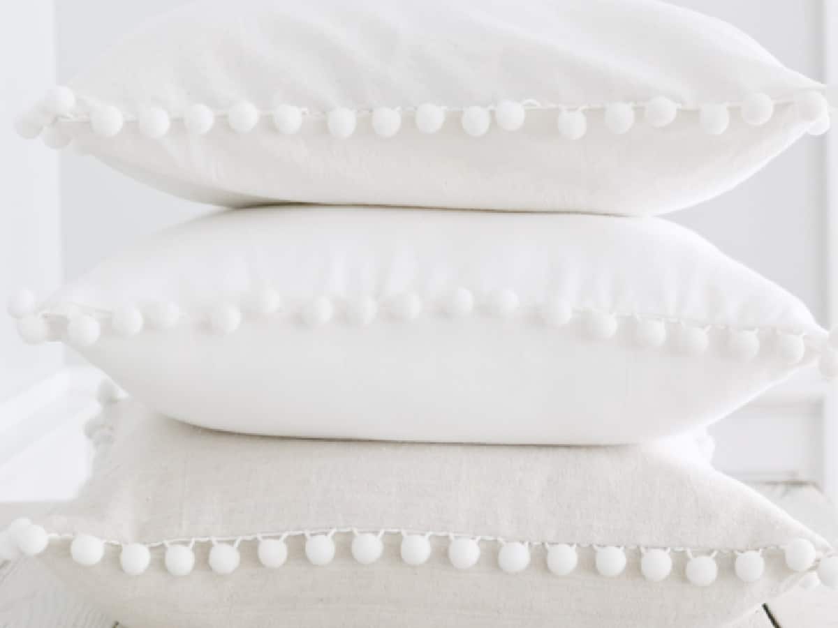 stack of 3 white pillows with pom pom fringe