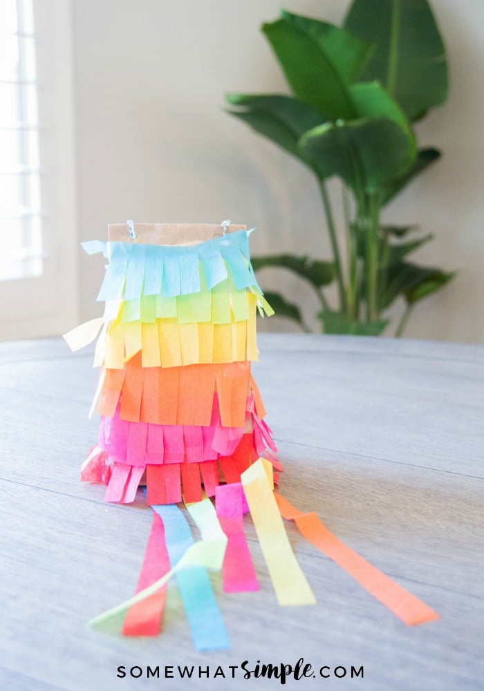 a colorful pinata made out of a paper bag sitting on a wooden table