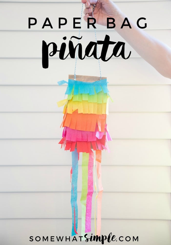 a hand holding a mini pinata that was made with a brown paper bag and colorful construction paper. The words paper bag pinata are written at the top of the image.