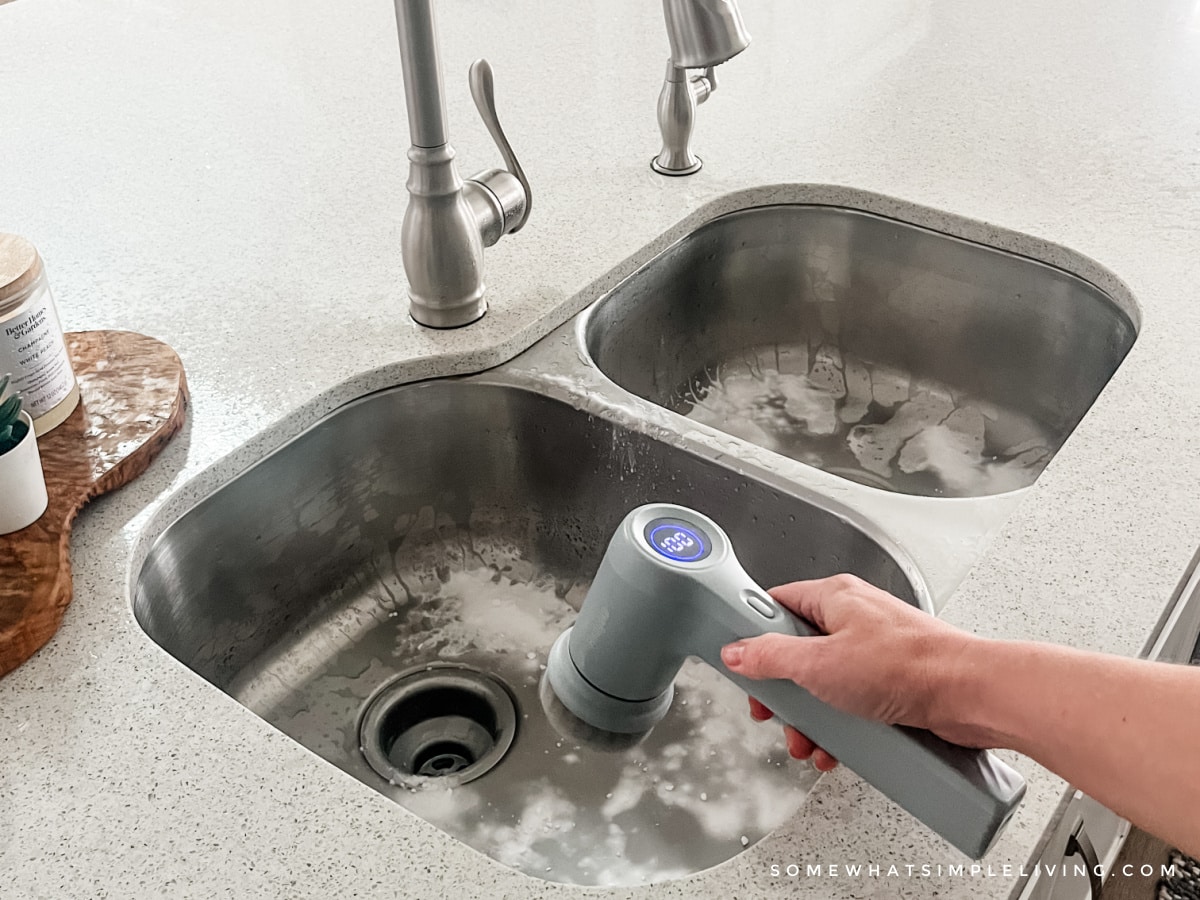 scrubbing a sink with baking soda and a scrub brush