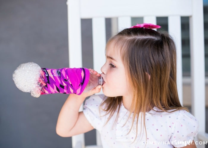 little girl blowing on a bubble snake