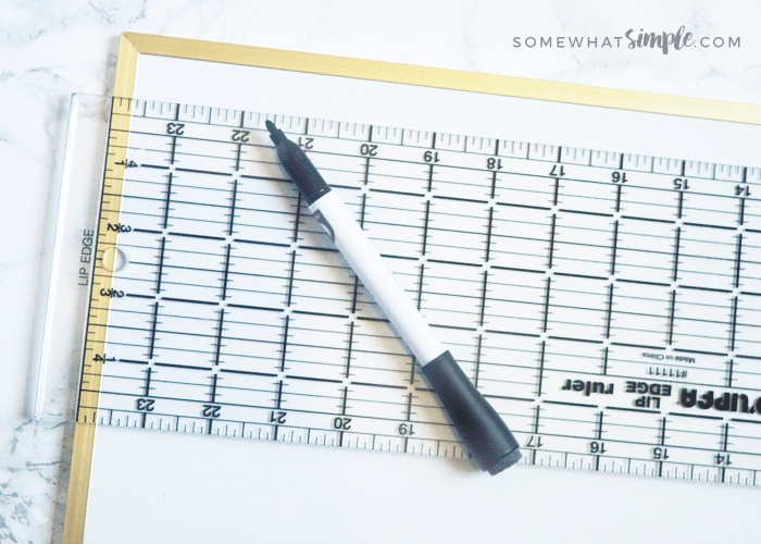 a white magnet board with a ruler and a marker laying on top of it