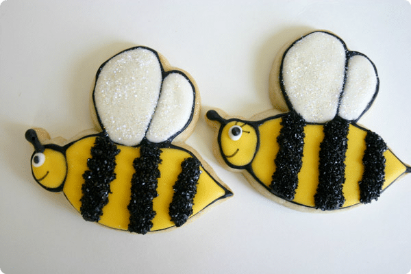 two yellow and black bumble cookies on a white background