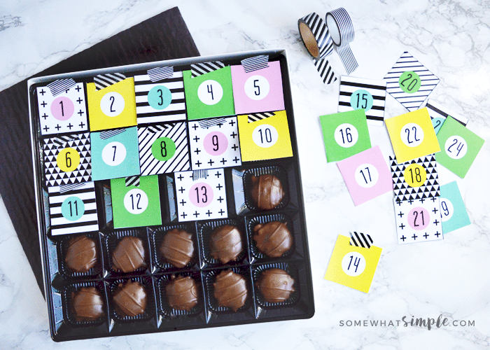 a box of chocolate covered with 13 of the advent caldendar printable with the rest in a pile on the counter