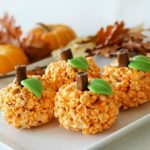 four Orange Halloween popcorn pumpkin balls on a white serving tray