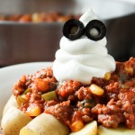 goulash plated over potatoes with a sour cream ghost piped on top