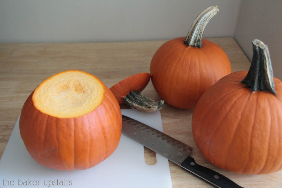 three pumpkins on a counter and one of them has the stem and the top cut off