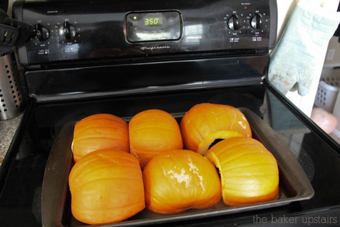 6 halves of pumpkins laying face down on a baking sheet on top of an oven