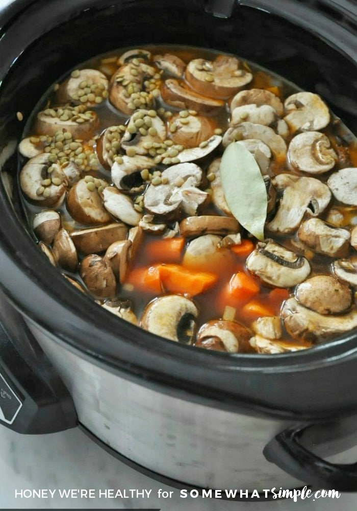 slow cooker filled with broth, mushrooms, lentils and carrots