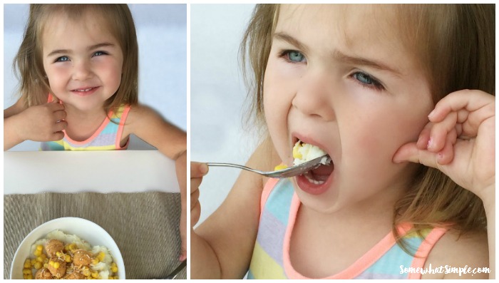 a little girl eating a bite from a chicken and mashed potato bowl