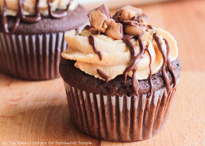 close up of a chocolate Reese's Peanut Butter Cupcake on a wood table with another cupcake in the background