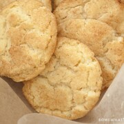 A close up of three soft snickerdoodle cookies topped with cinnamon and sugar with in a container lined with parchment paper