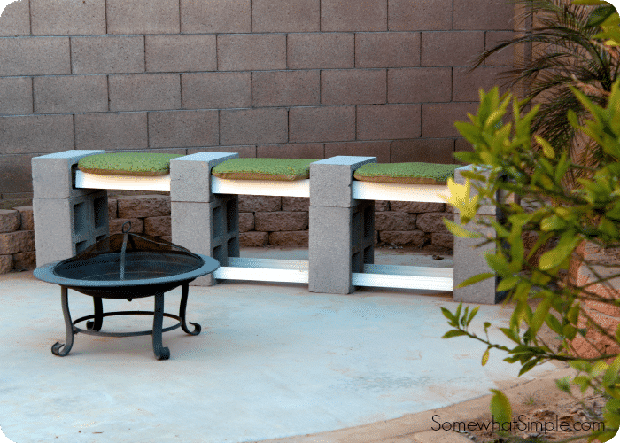 a cinder block bench with cushions on a patio next to a portable fire pit