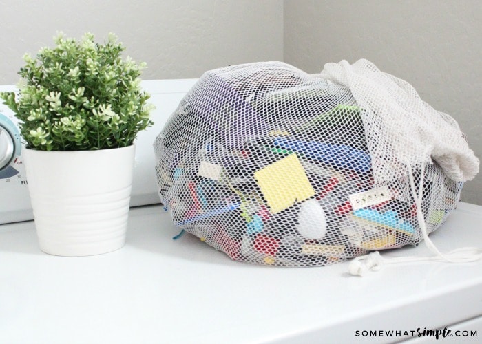 a laundry bag full of toys sitting on top of a washing machine.