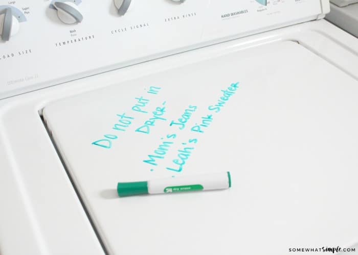 a dry erase marker laying on the top of the dryer with the words "do not put in dryer - mom's jeans, leah's pink sweater"