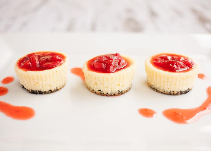  mini gâteaux au fromage faits avec un fond Oreo et une garniture de fruits sur un plateau de service.