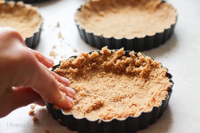 pressing a graham cracker crut into a pie tin