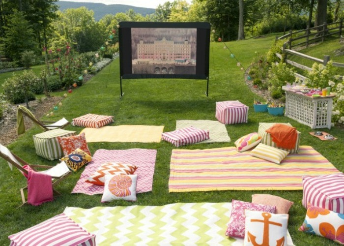 outdoor movie night with blankets and pillows laid on the grass is a fun bbq activity