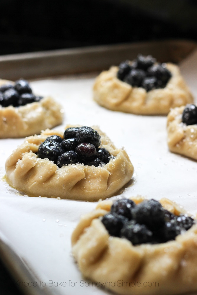 several uncooked Blueberry Galettes on a baking sheet getting ready to go into the oven