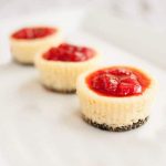 three mini cheesecakes with an Oreo crust topped with strawberries.
