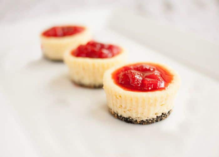  tres mini pasteles de queso con una corteza de Oreo cubierta con fresas.