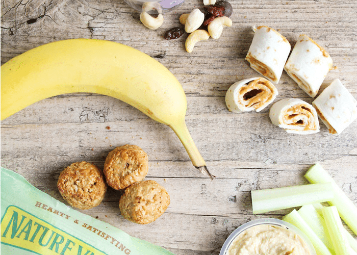 a granola bar, a banana, bite-sized pieces of a sandwich, celery sticks and nuts laying on a counter are easy snacks