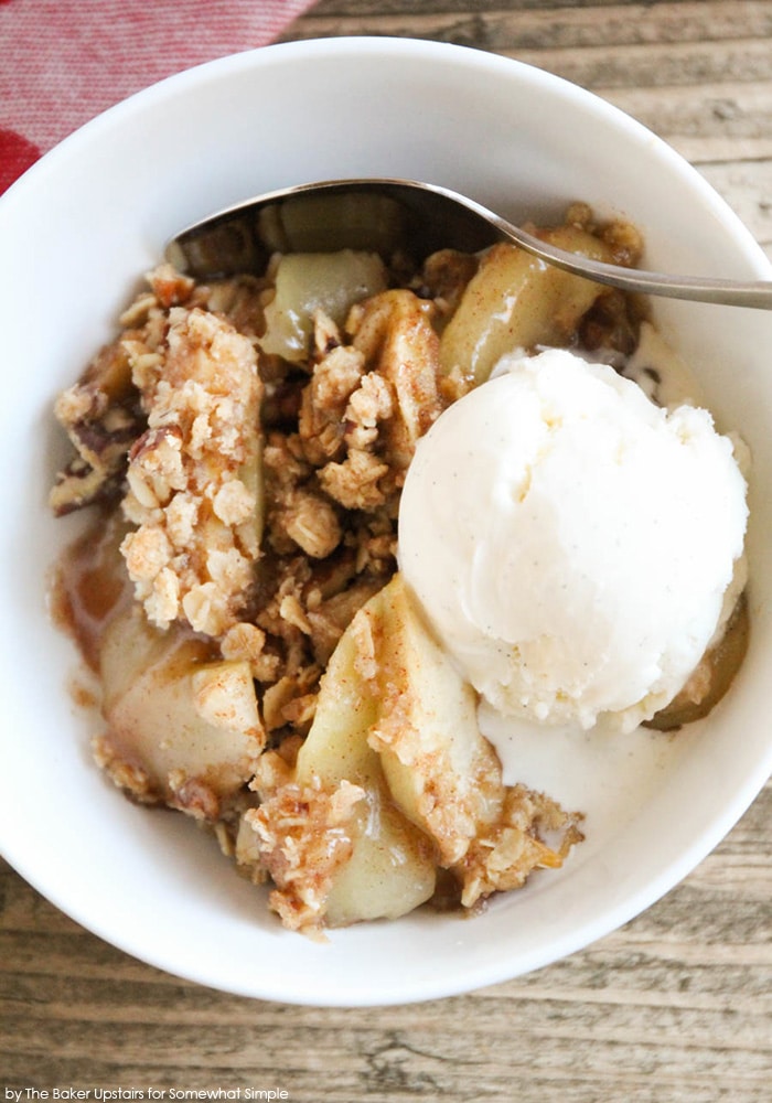 easy Apple Crisp recipe in a white bowl with a scoop of vanilla bean ice cream and a spoon.