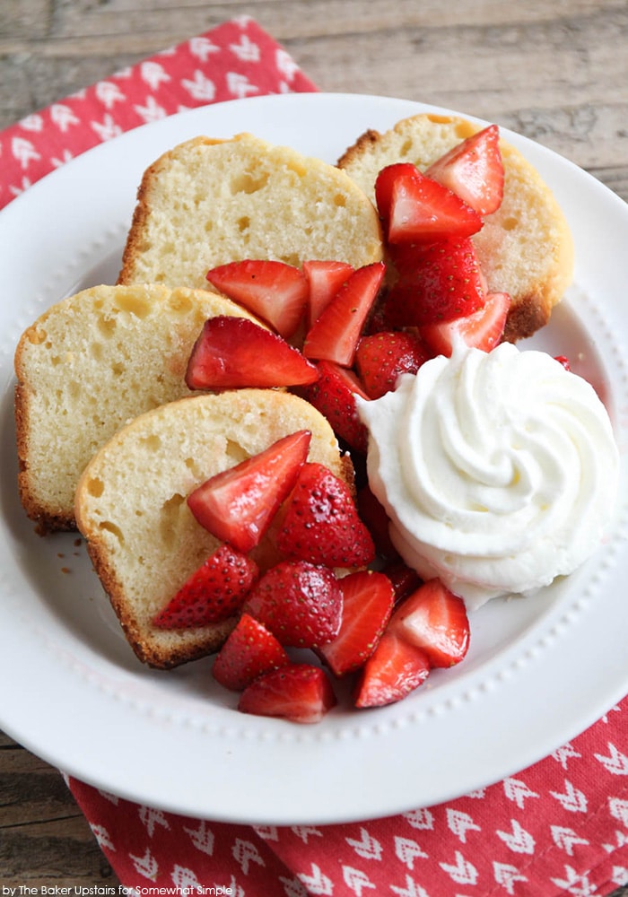 slices of this Vanilla Almond Pound Cake Recipe on a white plate topped with strawberries and whipped cream