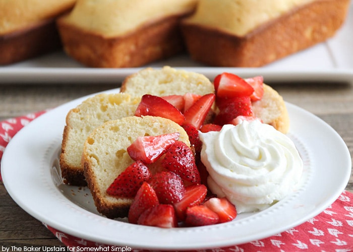 a white plate with four slices of Vanilla Almond Pound Cake made with this easy Recipe and topped with strawberries and whipped cream