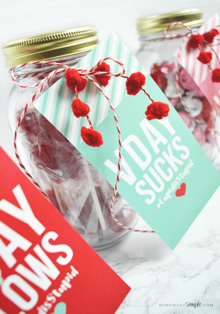 mason jars filled with suckers with galentine's day tags on them that say "VDAY SUCKS"