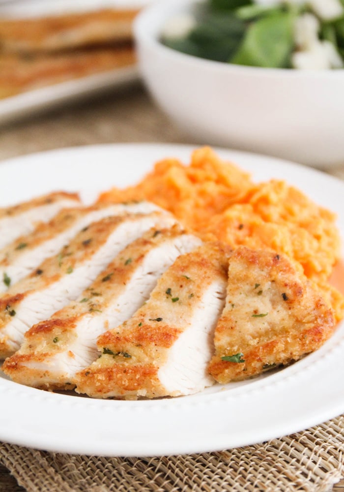 golden brown sliced Parmesan crusted Turkey Breast Cutlets on a white plate with cheesy mashed potatoes