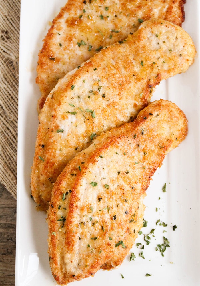 cooked golden brown garlic Parmesan Turkey Cutlets on a white serving tray