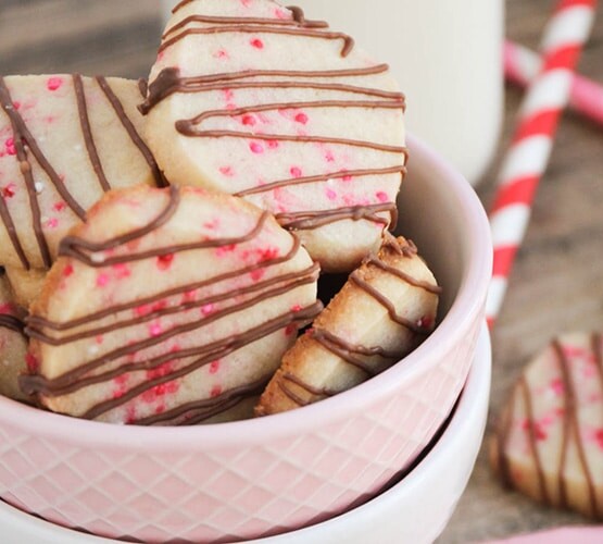valentine shortbread cookies drizzled with chocolate in a pink bowl