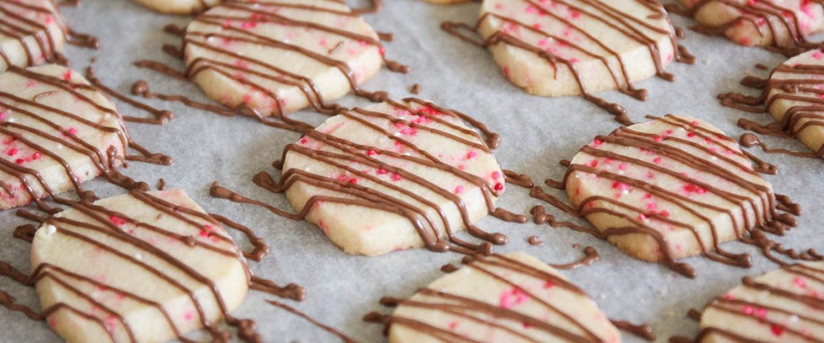 drizzling chocolate over valentine cookies
