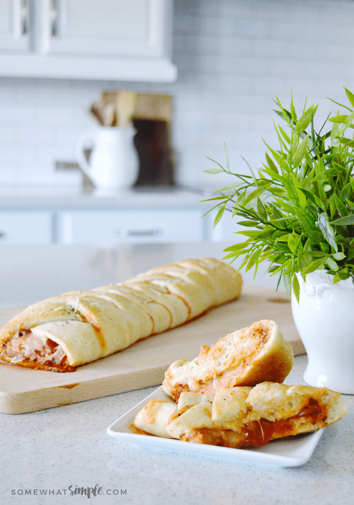 calzones sitting on a cutting board and a slices of the homemade calzone sitting on a white plate