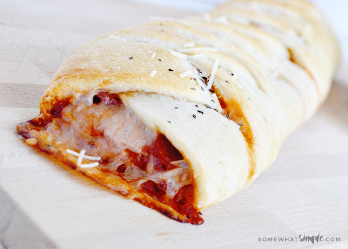 close up picture of cheese, marinara sauce and pepperoni dripping out of the end of this easy homemade calzone