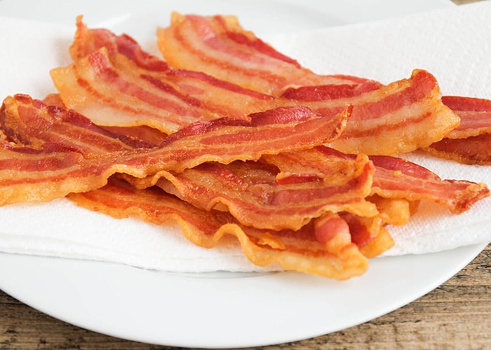 a plate of bacon on a white plate made using this method for the best way to cook bacon