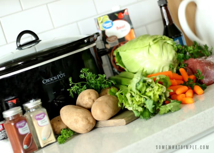 the ingredients to make corned beef and cabbage in the crock pot; potatoes, celery, cabbage, corned beef, spices and broth.