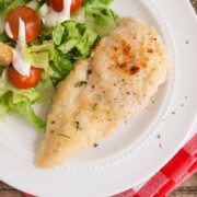 looking down on a plate with a piece of baked italian dressing chicken with a side of salad