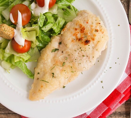 looking down on a plate with a piece of baked italian dressing chicken with a side of salad
