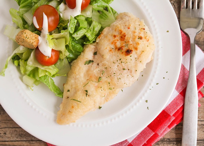 looking down on a plate with a piece of baked italian dressing chicken with a side of salad