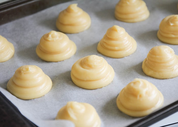 raw cream puff dough on a baking sheet