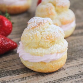 close up of a cream puff next to a strawberry