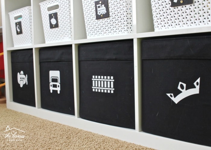 a wooden white shelf with different compartments. Each on has either a white basket or a black bin inside