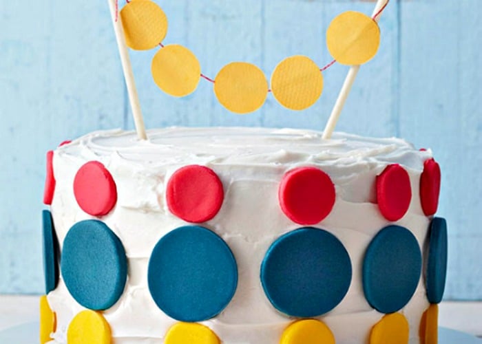 a cake with white frosting that has large red blue and yellow dots