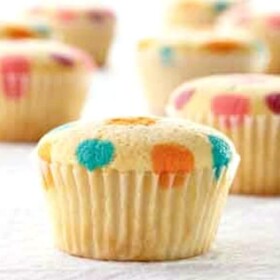 vanilla cupcakes with orange blue yellow red and purple polka dots