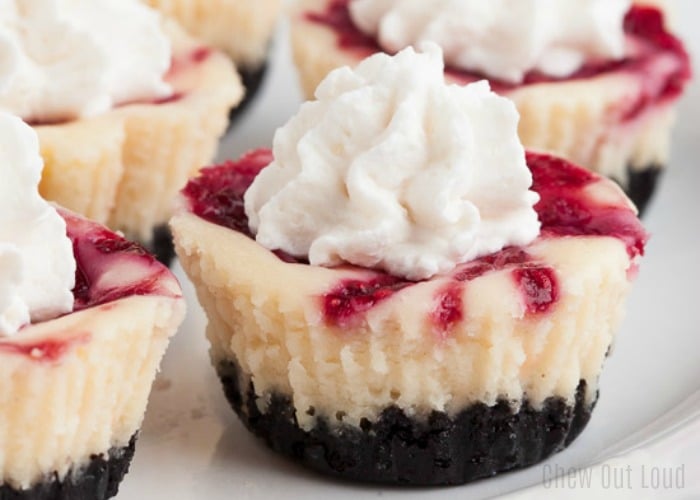 a close up of raspberry cheesecake bites topped with whipped cream