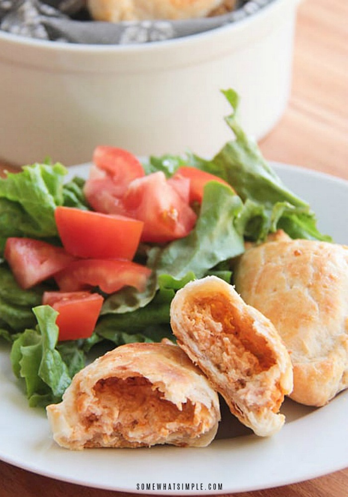 an empanada de pollo that has been cut in half and placed on a plate. The empanada is filled with chicken and cheese and is next to a garden salad.