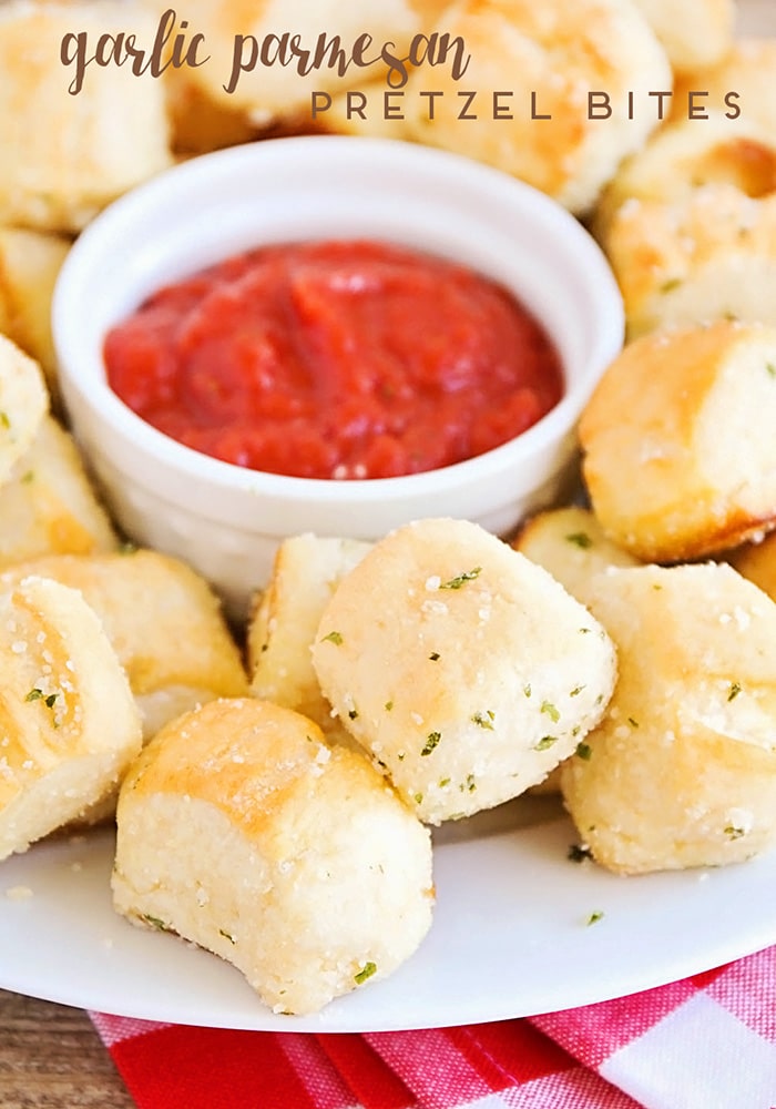 homemade soft Garlic Parmesan Pretzel Bites on a plate that were made using this easy recipe with a small white bowl of red sauce in the middle. the words, garlic parmesan pretzel bites is written at the top of the image