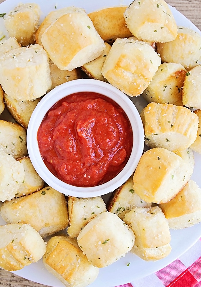 looking down on a plate of homemade soft Garlic Parmesan Pretzel Bites with a small dish of marinara sauce in the middle.